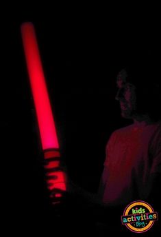 a man holding a red light saber in the dark