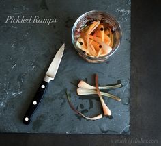 a glass bowl filled with sliced carrots next to a knife