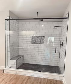 a bathroom with white tile and wood flooring on the walls, along with a walk in shower