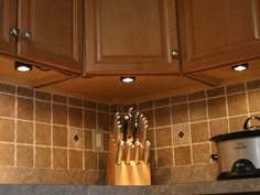 a kitchen with wooden cabinets and utensils on the counter top in front of it