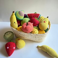 crocheted fruits and vegetables are in a basket on the table next to two small stuffed animals