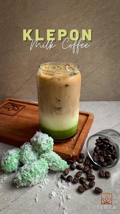 a cup of coffee sitting on top of a wooden tray next to some green stuff