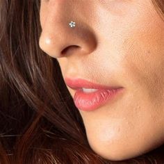 a close up of a woman's face with a nose piercing in the middle