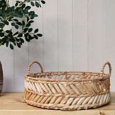 a basket sitting on top of a wooden table next to a potted plant