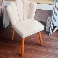 a white chair sitting on top of a hard wood floor next to a desk with a laptop