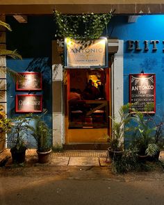 a blue building with plants growing out of it's front door and lit up windows