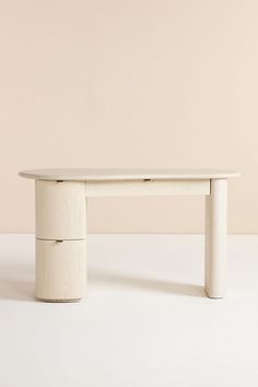 a white table sitting on top of a white floor next to a wall with a light colored background