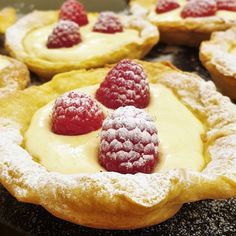 raspberries and cream on top of pastry crusts