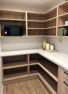 an empty kitchen with wooden cabinets and white counter tops, along with wood flooring