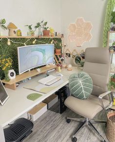 a computer desk with a monitor, keyboard and mouse on it in front of plants