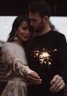 a man and woman holding sparklers in their hands