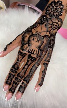 a woman's hand with hennap and flowers painted on the top of it