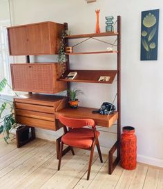 a wooden desk sitting next to a tall shelf filled with books and other items on top of it