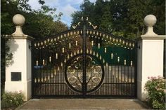 an ornate iron gate with gold bells on the top and bottom bars, surrounded by white pillars