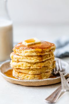 a stack of pancakes with butter and syrup on a plate next to a glass of milk