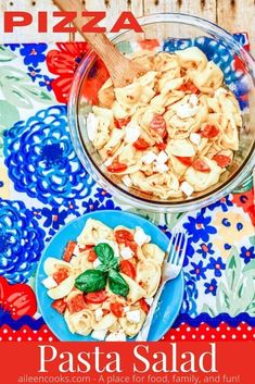 pasta salad with spinach and tomatoes in a glass bowl on a colorful tablecloth