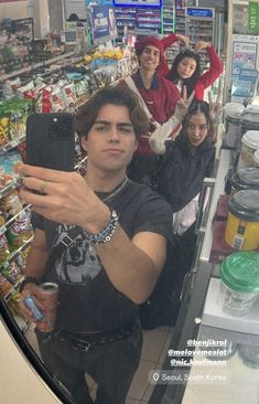 a man taking a selfie in front of a store with other people behind him