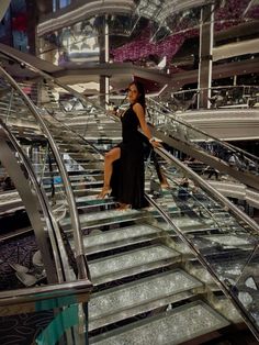 a woman in a black dress is walking down the stairs on an escalator