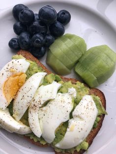 an open face sandwich with eggs, avocado and blueberries on a plate