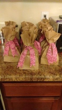 some brown paper bags with pink bows sitting on top of a kitchen counter next to a toaster oven