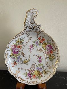 an ornately decorated dish on a wooden stand