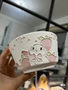 a hand holding up a white case with pink and green designs on it's sides