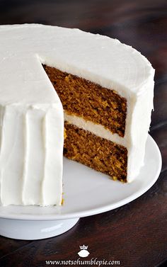 a carrot cake with white frosting is cut into slices and sits on a plate