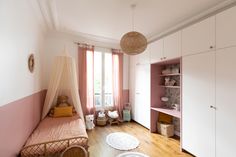 a pink and white room with a bed, dressers, and other items on the floor