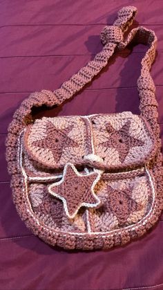 a crocheted purse sitting on top of a purple blanket with a star decoration