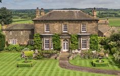 an aerial view of a large house with lots of greenery on the front lawn