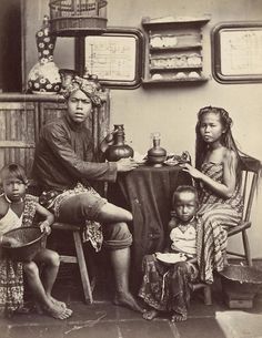 an old black and white photo of three people sitting at a table with two children