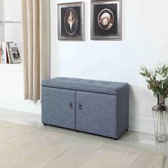 a blue storage bench sitting in front of a window next to a vase with flowers