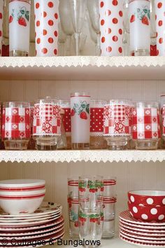 red and white dishes are on shelves with polka dot cups, glasses, and candles