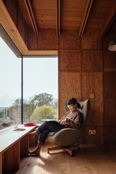 a woman sitting in a chair looking out the window