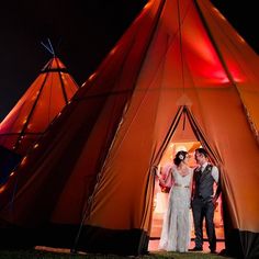 a bride and groom standing in front of a tippy tent with lights on it