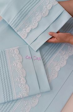 a woman is holding several pieces of light blue paper with white lace on it,