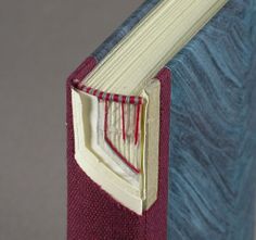 an open book with red thread on the pages and a pocket in the front cover