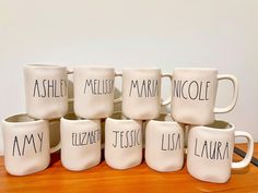 six coffee mugs sitting on top of a wooden table with names painted on them