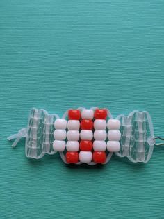 an object made out of plastic beads on a blue surface with white and red dots