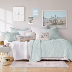 a bed with blue and white comforters in a bedroom next to a window, framed pictures on the wall