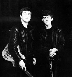 two men standing next to each other holding guitars