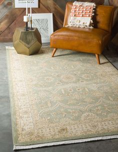 a brown chair sitting on top of a wooden floor next to a rug and lamp