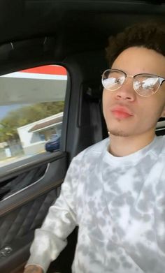 a man with glasses sitting in the back seat of a car