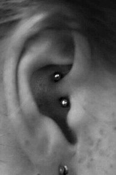 a black and white photo of a person's ear with two piercings on it