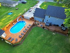 an aerial view of a backyard with a swimming pool and decking area, surrounded by lush green grass