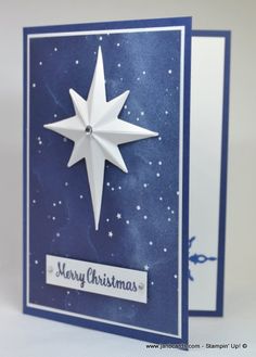 a christmas card with a white paper star on it and the words merry christmas written in blue