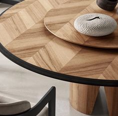 a wooden table with two black chairs and a white vase on it's side