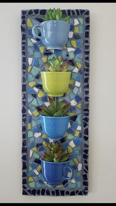 a blue and yellow wall hanging with succulents on it's side