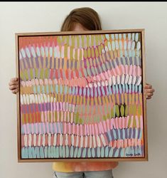 a person holding up a painting with different colors