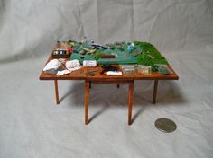 a miniature table with many items on it and a coin sitting next to it in front of the table